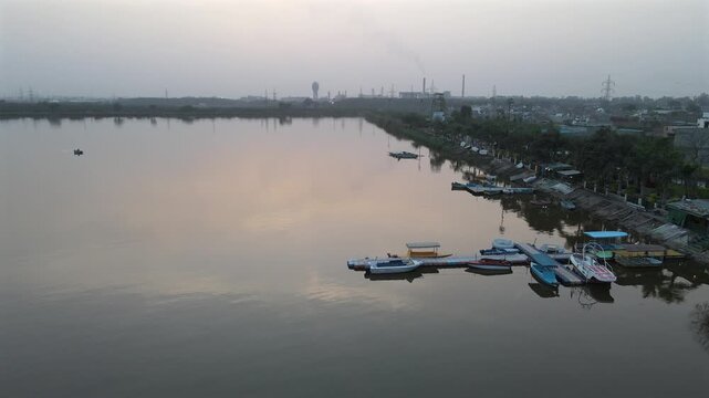 Peaceful Aerial Sunset over Bathinda Lake Boating Dock with Industrial Horizon.