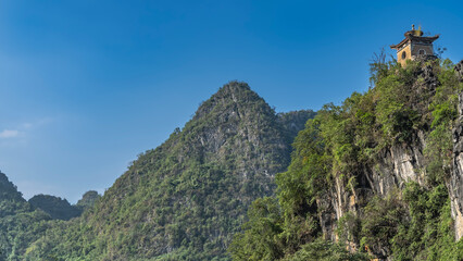 Obraz premium Picturesque mountains against the blue sky. At the top is a Chinese pagoda with a curved roof. Green vegetation on the slopes. China. Copy space.