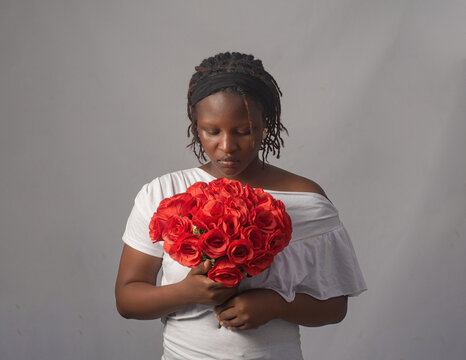 Beautiful African Woman Holding Red Rose Bouquet with Head Down