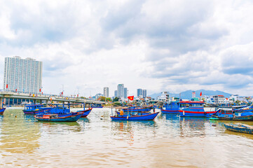 Cai River with fishing boats and bridge in Nha Trang city on a cloudy day. Panorama view of the Nha Trang in Vietnam