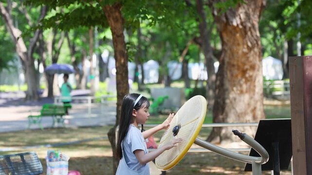 Young Asian Girl Spinning Exercise Wheel at Outdoor Public Park Playground