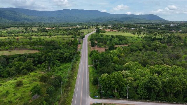 High-angle drone footage of a winding mountain road cutting through dense green forest, capturing natural landscape, scenic travel route, and peaceful countryside environment from above.