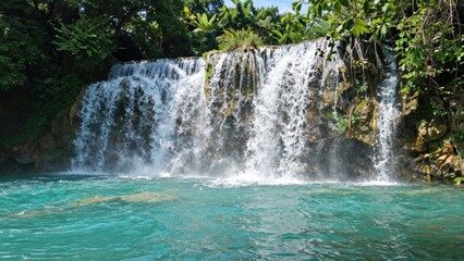 Fototapeta premium Waterfall cascading into turquoise pool in tropical river