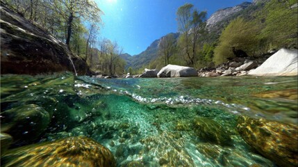 Fototapeta premium Crystal Clear River Flowing Through Lush Green Mountains Under a Bright Sunny Sky