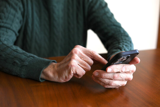 Retired senior man texting on his smartphone with aging hands