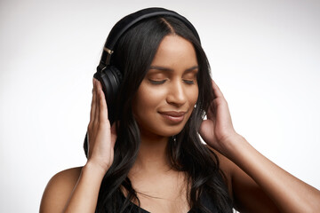 Fototapeta premium Woman, relax and headphones in studio with music, streaming song and hearing track for calm playlist. Female person, peace and audio tech for podcast, radio or listening to album on white background.