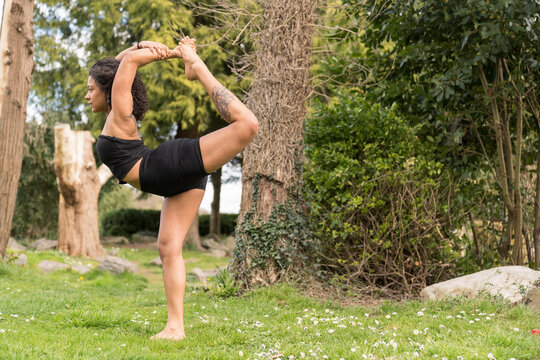 Woman practicing yoga king dancer pose in nature