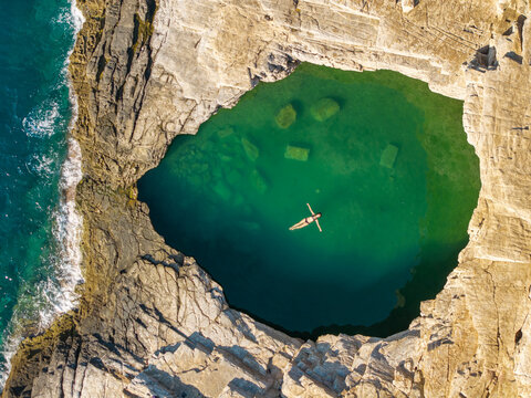 Aerial top down view of a woman floating in Giola Lagoon, Thasos, Greece