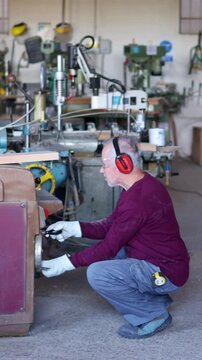 Senior carpenter operating thicknesser machine in his workshop