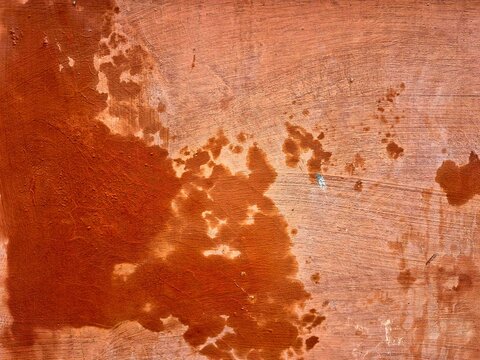Weathered terracotta orange wall texture with paint splatters and peeling layers
