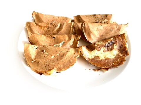 Traditional Indonesian crispy crepes known as Kue Leker served on a white plate, isolated on white background. Popular sweet street food snack with thin crunchy texture.