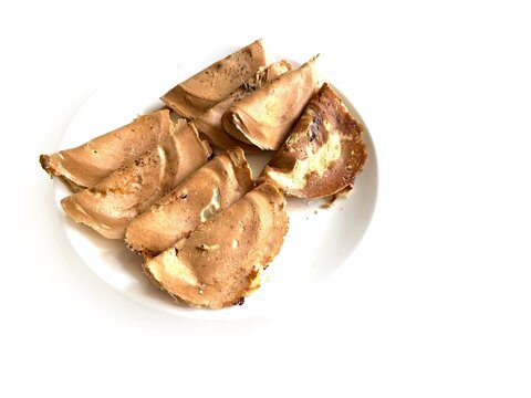 Traditional Indonesian crispy crepes known as Kue Leker served on a white plate, isolated on white background. Popular sweet street food snack with thin crunchy texture.