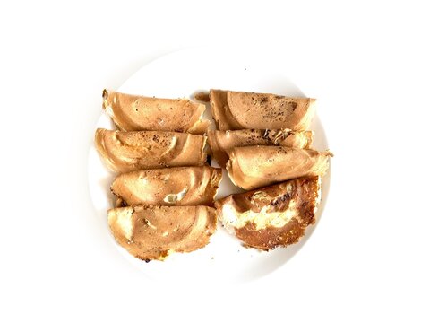 Traditional Indonesian crispy crepes known as Kue Leker served on a white plate, isolated on white background. Popular sweet street food snack with thin crunchy texture.