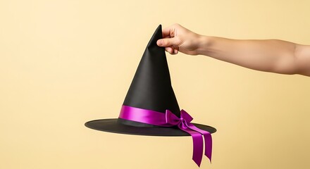 Fototapeta premium hand holding a black Halloween witch hat