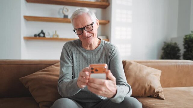 Elderly man surfing internet by modern smartphone, using mobile app for shopping . Modern technology and aged people, senior male user testing new application for communication, phone addiction