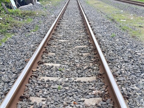 Railway tracks extending into the distance, gravel ballast, and green grass.