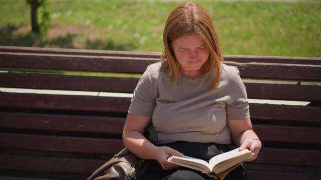 Student sitting on wooden bench outdoors reading book under warm sunlight gradually loses interest then closes it thoughtful peaceful summer atmosphere surrounded by green grass