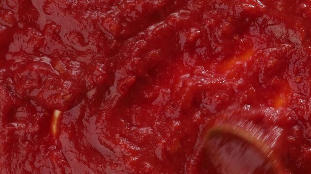 top view of red tomatoes sauce mixing with spoon food texture