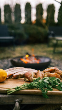 Preparing raw meat and sausages for grilling over an outdoor fire pit