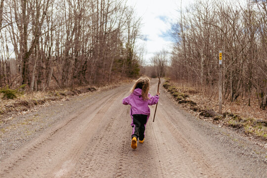 Kindergartener running in yellow boots and rain suit