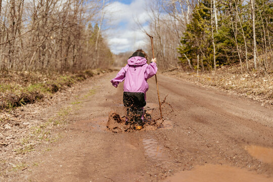 Child splashing in spring rain puddle
