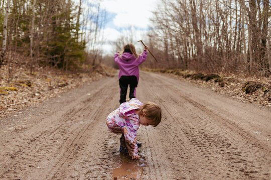 Kids exploring mud puddles with spring sunshine