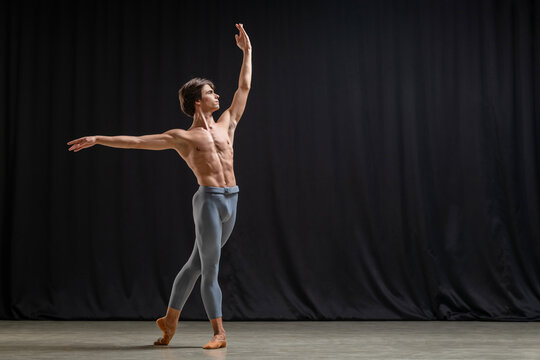 Professional male ballet dancer practicing classic dance on stage.