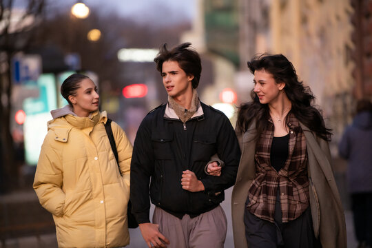 Group of young friends walking down city street.