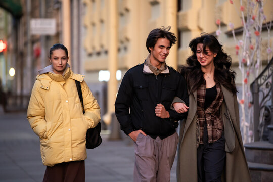 Group of young friends walking down city street.