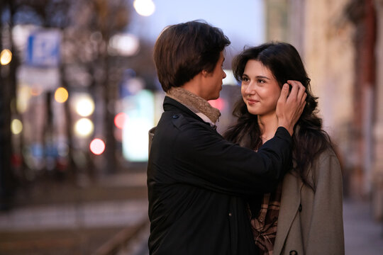 Romantic couple sharing intimate moment on city street at dusk.