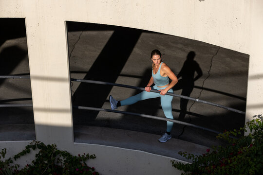 Athletic 30 year old woman running in a parking structure at sunset