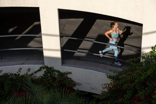 Athletic 30 year old woman running in a parking structure at sunset