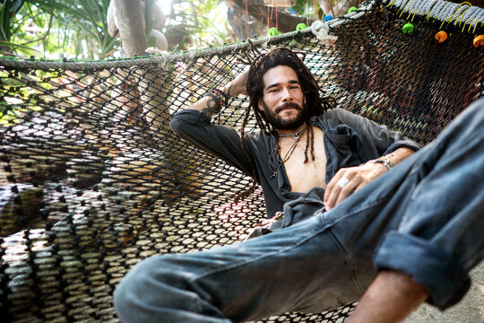 handsome fashion guy with dreadlocks on the beach lies on a hamm