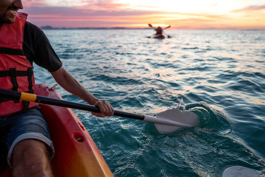 guy in kayaks in the sea at sunset