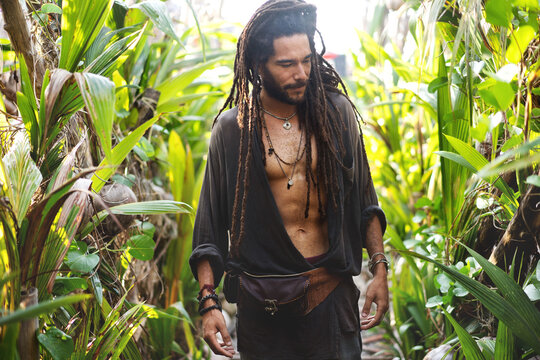 fashion guy with dreadlocks in tropical palm trees smiling