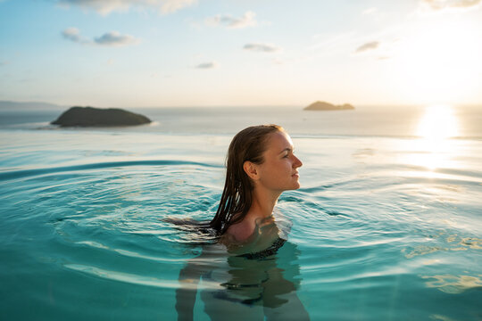 A girl in a pool at sunset in Thailand.