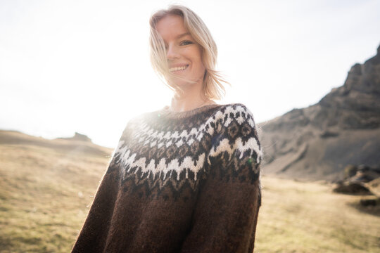 A girl wearing an Icelandic sweater stands on an island