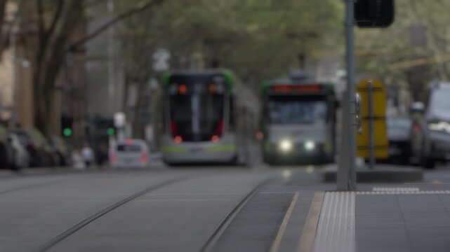 Street-level shot of Melbourne trams with shallow depth of field, creating soft background blur and strong subject isolation. Cinematic urban scene ideal for transport, commuting, and modern city life