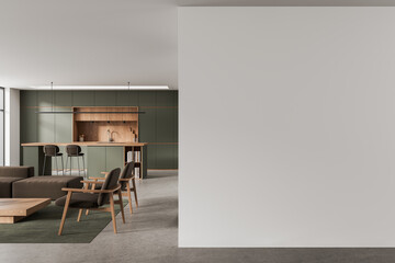 Modern minimalist interior featuring open kitchen with wooden accents, olive cabinetry, contemporary furniture and large blank wall mockup for design presentations. 3D Rendering