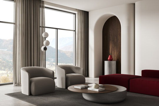Modern interior living room with soft armchairs, large windows, mountain view, round table, elegant curtains, arched niche and minimalist decor. 3D Rendering