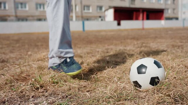 player positions foot carefully, skilled athlete aligns foot meticulously before executing powerful shot, experienced player approaches ball with steady stance on wellused local soccer field