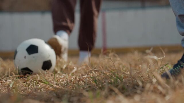 feet expertly maneuvering over rough terrain, two athletes coordinating precise kicks on uneven turf surface, closeup of players executing skillful ball control during competitive match