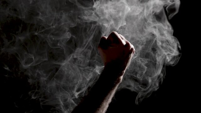 Silhouetted human hand reaching through dense swirling white smoke against a dark background, creating a dramatic, moody atmosphere with strong contrast and subtle copy space