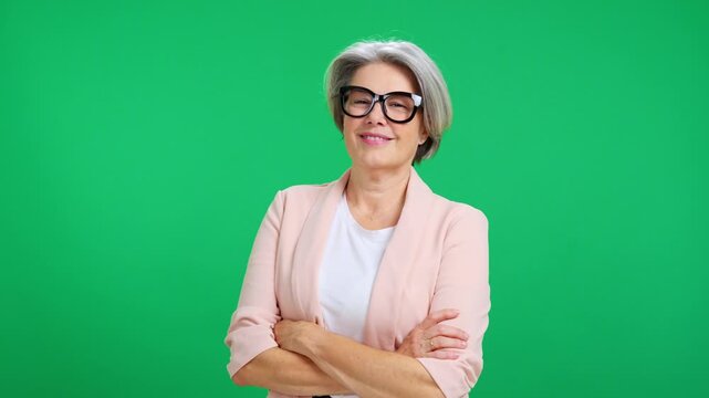 Senior businesswoman crossing arms with confidence on green screen