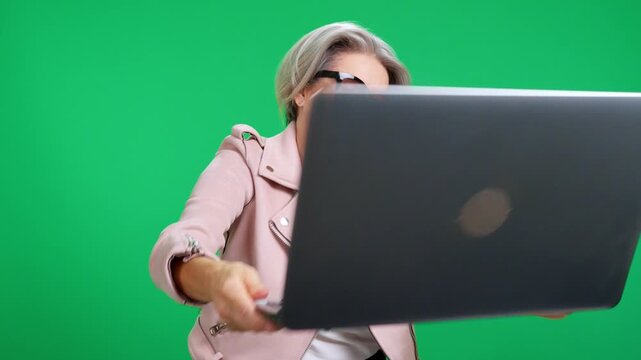 Smiling businesswoman comically hitting her head with a laptop
