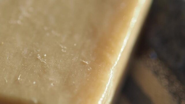 Macro close up of hard cheese texture with crystallized salt and waxy surface on dark wood.