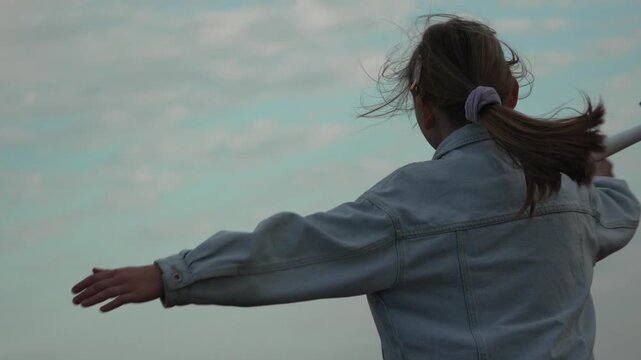 Girl playing toy airplane, young dreamer having fun outdoors, imagining flying in the sky with freedom and joy