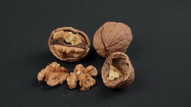 Close-up macro of walnut processing stages: whole, cracked open, and shelled kernels on a black background. Premium natural food concept.