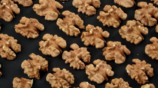 Densely packed infinite pattern of raw whole walnuts in shell. Extreme macro close up highlights the rugged texture and brain-like shape. Premium conceptual background.