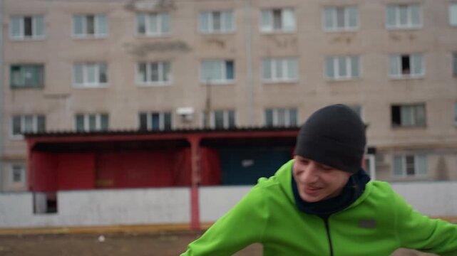 joyful sprint through greenery near city buildings, energetic game between man and woman in outdoor setting, lively chase across open field with apartment complexes behind on cloudy day